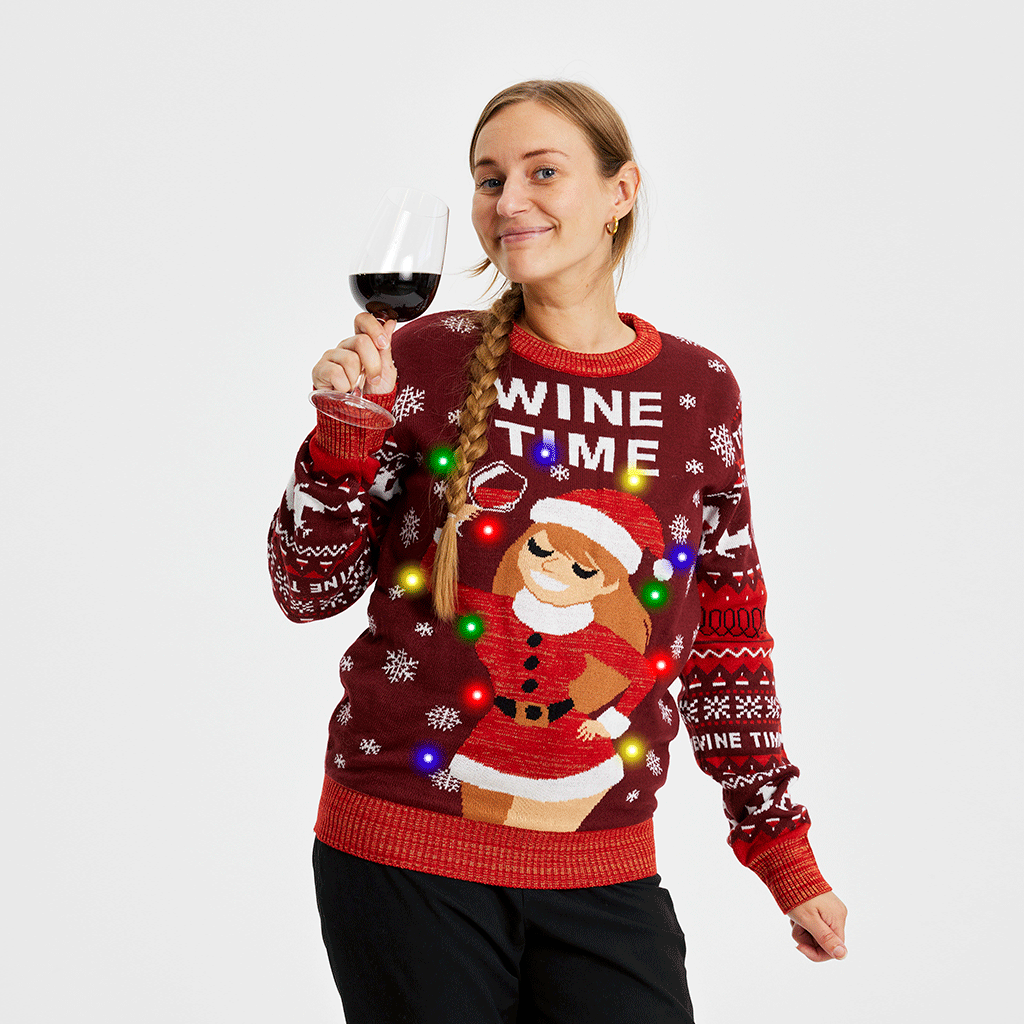 Una donna con un bicchiere di vino che indossa un maglione rosso natalizio con la scritta